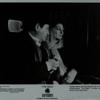 Black and white photograph featuring Donal McCann and Angelica Huston in the back of a carriage on the set of 