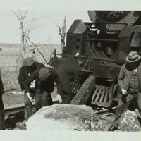 Black and white photograph of a rail line being cleared of rocks in the western United States.